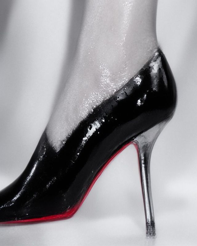 Redonnoir Fine-Art Foto ‚Millimeter Rot‘ — elegante Frau in Schwarz mit rot lackierter Stiletto-Sohle, A Millimeter of Red, editorial Schwarzweiss mit rotem Farbakzent.